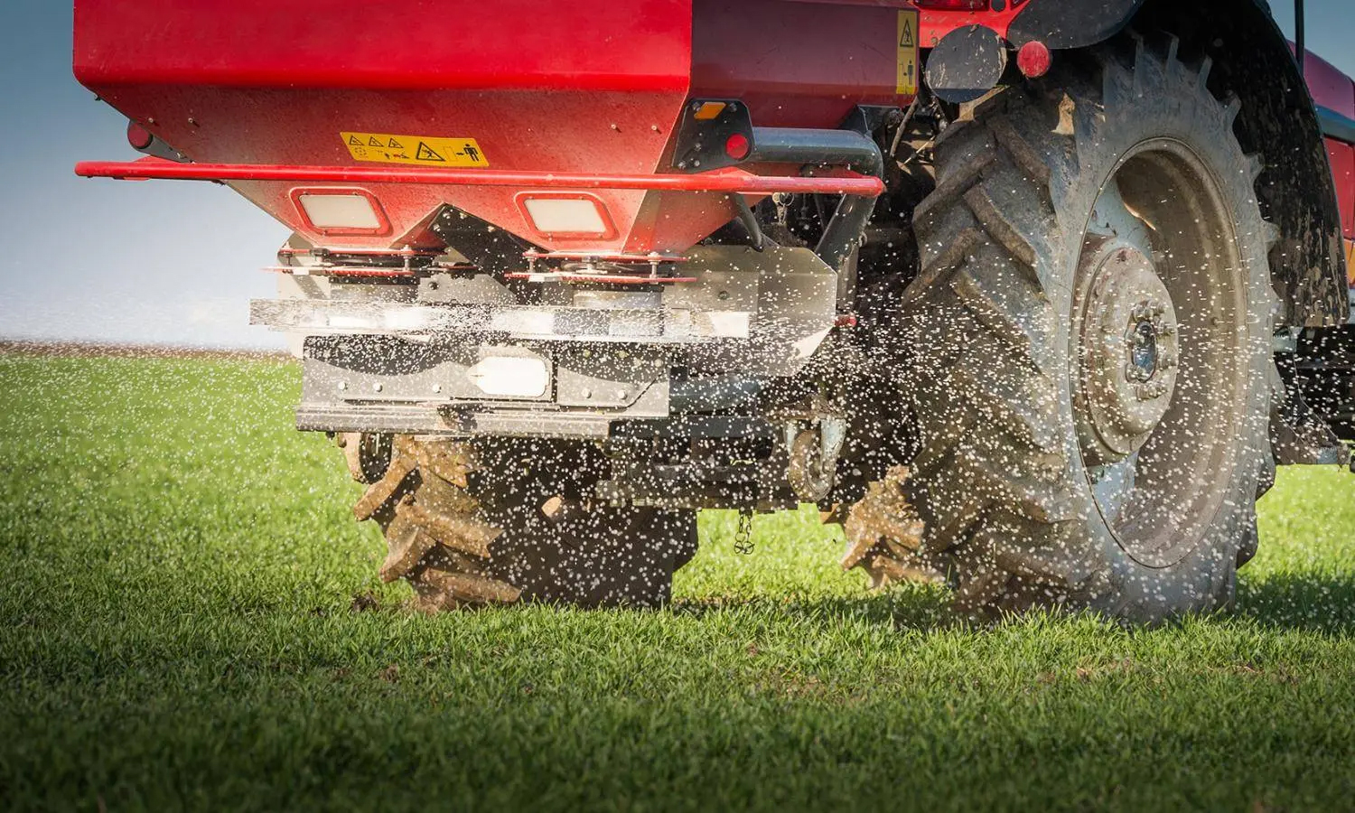 A tractor spreading fertilizer on the field