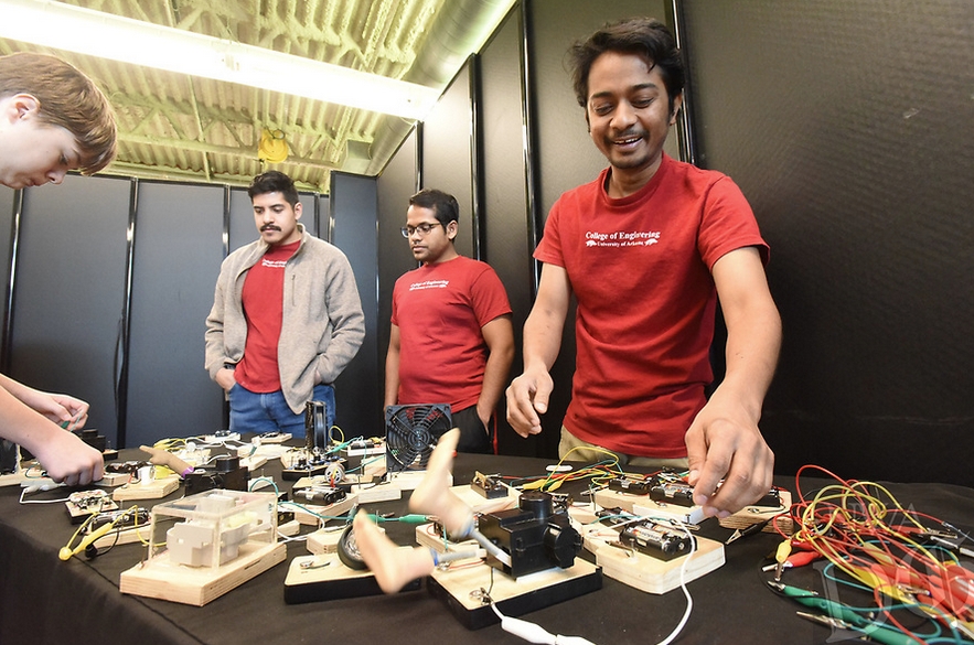 An electrical engineering student from the University of Arkansas, right, completes a circuit that gets legs kicking at the "Wonders of Wattage."